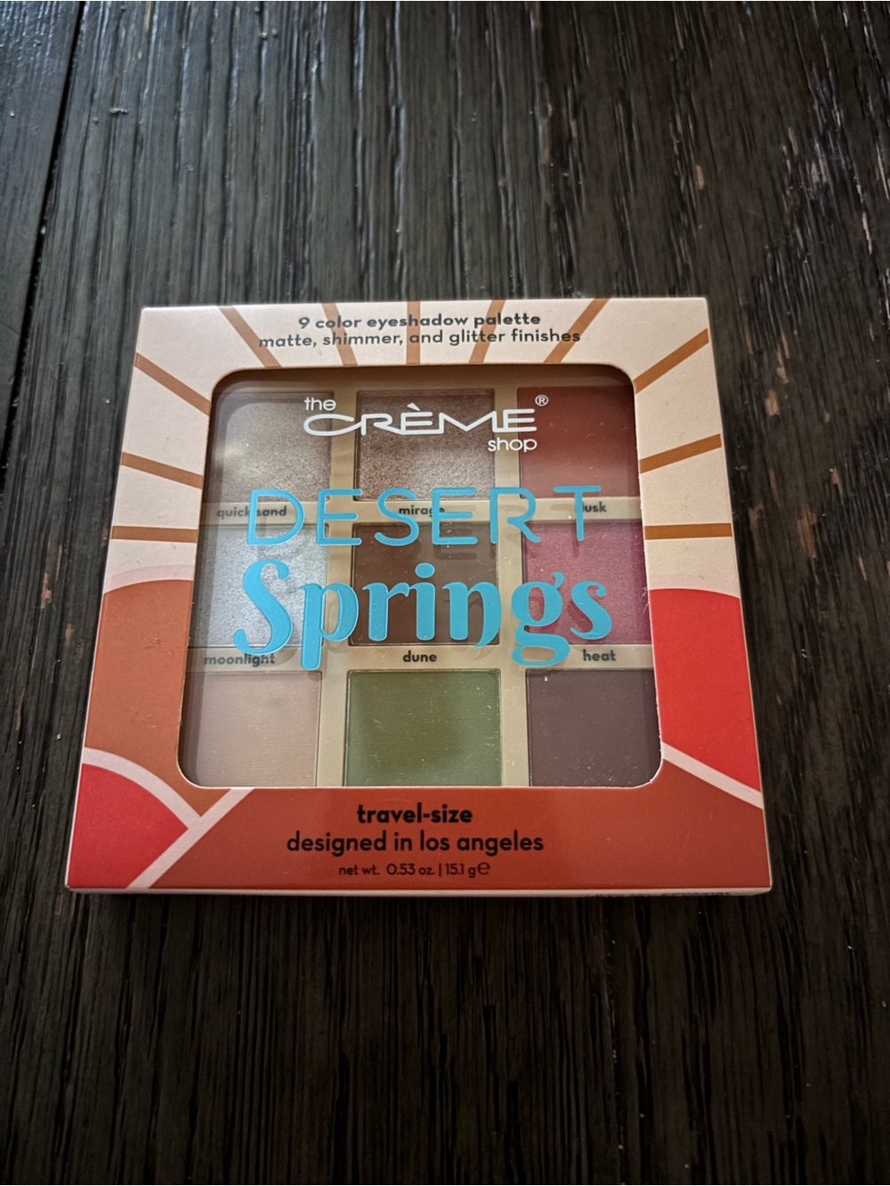 Cosmetic eyeshadow palette on dark wood